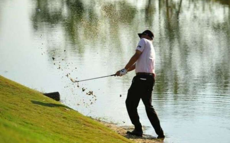 Golfer thực hiện cú swing để cứu bóng ra khỏi bẫy nước